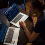 A trader analyzing charts on a computer screen and talking about trading psychology tips over the phone.
