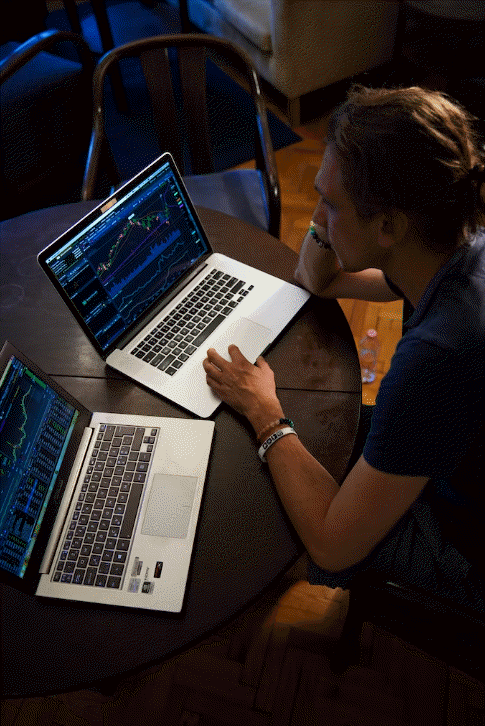A trader analyzing charts on a computer screen and talking about trading psychology tips over the phone.